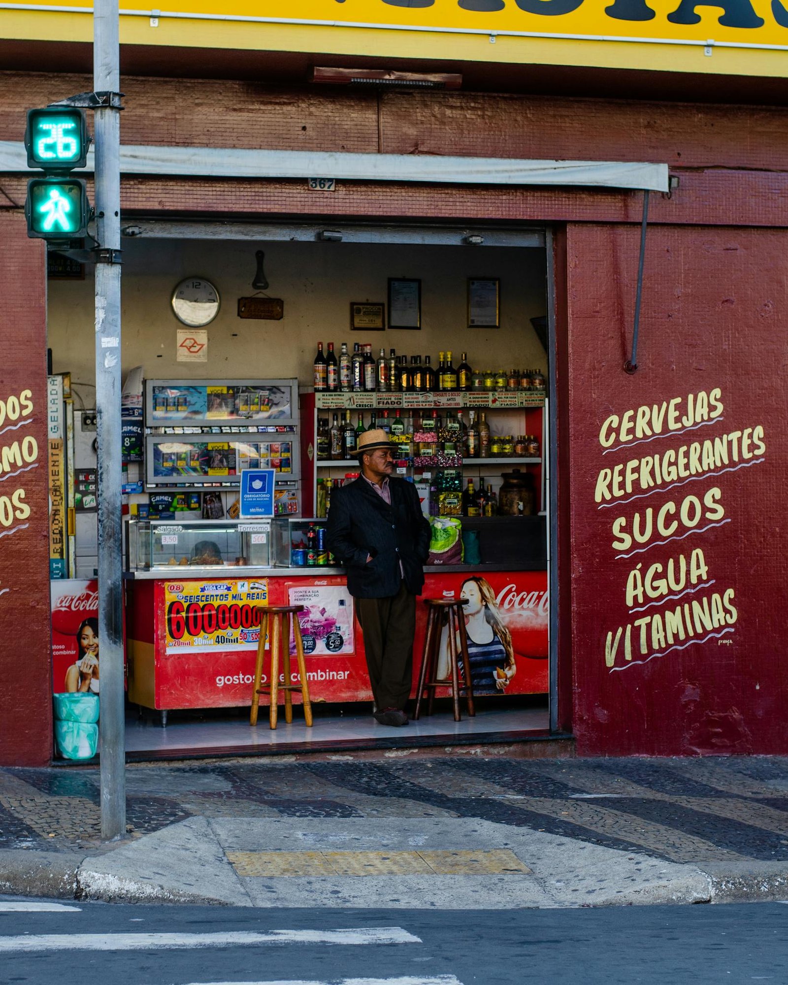 A man stands in the entrance of a convenience store with vibrant signage.